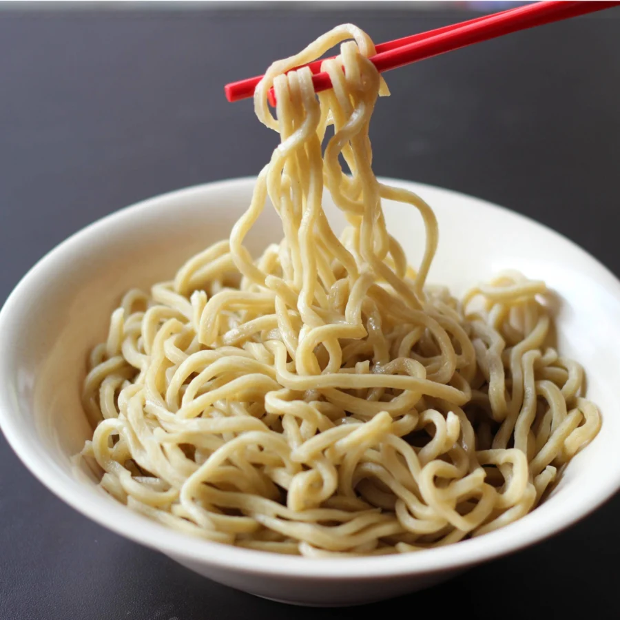 A pair of chopsticks lifting plain boiled noodles.
