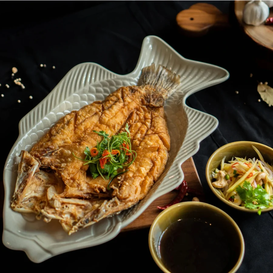 A deep-fried sea bass served with sides.
