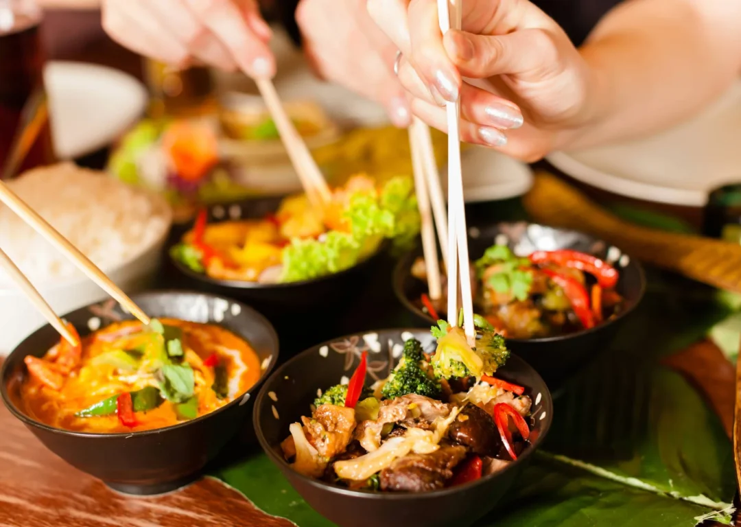 A group of friends eating a selection of Thai dishes.