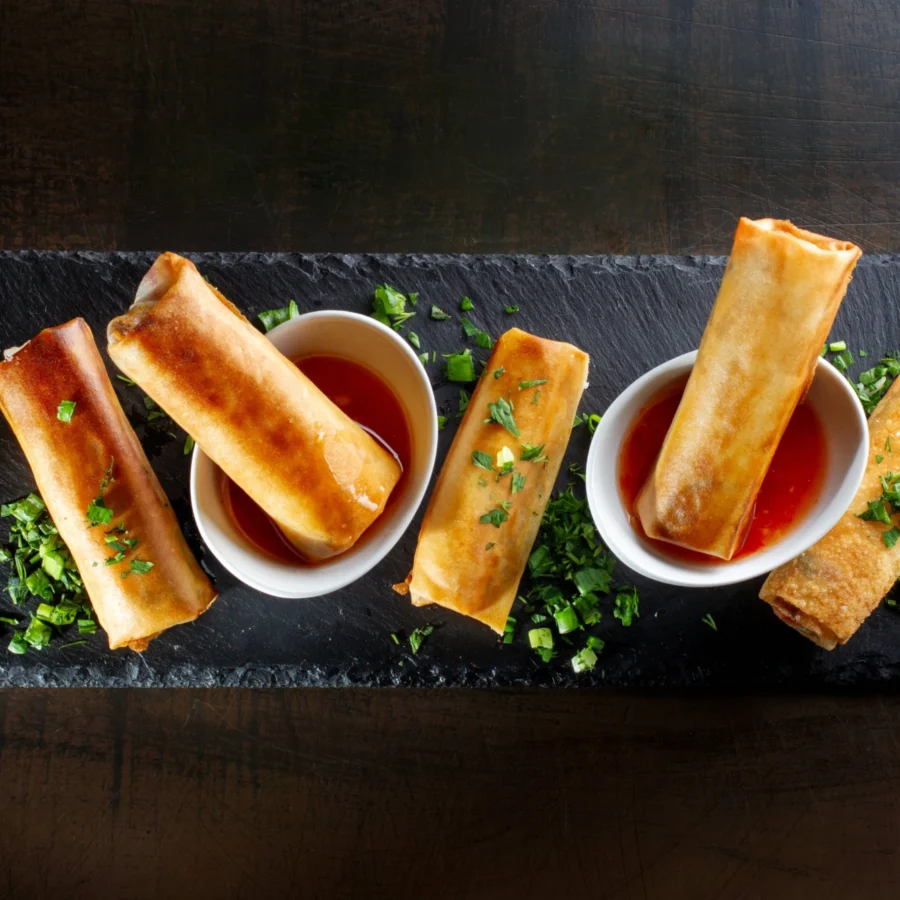 A slate with spring rolls and dipping sauce.
